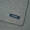 A close-up of a gray knitted scarf with a dark blue label. Anteprima dell’immagine prodotto