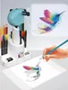 A drawing projector is shown with colored pencils and a hand drawing a hummingbird. Voir les images du produit