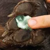 A finger is applying a green balm to a dog's paw. Produktbild-Vorschau