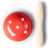 A red mushroom-shaped object with white dots and a wooden handle, photographed from above on a white background. Produktbild-Vorschau
