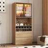 A tall, wooden cabinet with glass doors and LED lighting, designed for storing wine and spirits, is shown in a room setting. Náhled obrázku produktu
