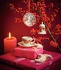 A festive Christmas still life with a lit candle, wrapped gifts, a cup of coffee, and ornaments hanging from a branch with red berries. Produktbild-Vorschau