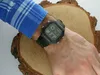 A person's arm wearing a watch is resting on a wooden surface. Produktbild-Vorschau