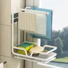 A white kitchen organizer rack with towels, sponges, soap, and brushes, placed near a window with a view of trees and water. Produktbild-Vorschau
