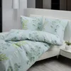 A neatly made bed with a light blue and green botanical print duvet cover and pillows. Produktbild-Vorschau