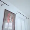 A modern interior with a large framed artwork of a lion and two curtain rods mounted on the wall above a window with blinds. Podgląd zdjęcia produktu