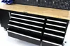 A close-up view of a black rolling workbench with a wooden top and multiple drawers with silver handles. Produktbild-Vorschau