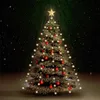 A decorated Christmas tree with lights and ornaments, set against a dark, snowy background with green light rays emanating from the top. Podgląd zdjęcia produktu