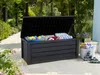An open storage box filled with cushions and toys, placed on a patio next to a white basket with more items. Produktbild-Vorschau