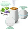 A white aroma diffuser with a wooden top, emitting steam, surrounded by images of mint, lime, lavender, and vanilla beans, and close-ups of its control panel and LED light. Náhľad obrázku produktu