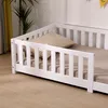 A close-up view of a white wooden child's bed with a guardrail and a beige checkered pillow. Náhľad obrázku produktu