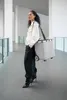A woman walks down a modern hallway carrying a rolling shopping bag. Produktbild-Vorschau