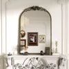 A decorative mirror above a fireplace mantelpiece, adorned with various decorative objects and framed pictures. Podgląd zdjęcia produktu