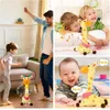 Gelbes Plüsch-Giraffenspielzeug mit rosa Tupfenschal, gezeigt beim Tanzen mit einem Kind und Interagieren mit einem Baby Podgląd zdjęcia produktu