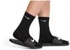 A close-up shot of a person's feet wearing black Nike socks and black Nike slides. Podgląd zdjęcia produktu