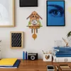 A cuckoo clock is displayed on a wall above a desk with various items. Náhled obrázku produktu