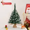 A small artificial Christmas tree with snow-like accents, placed on a table with gift boxes and a deer figurine. A fireplace with stockings and a Santa Claus poster is visible in the background. Anteprima dell’immagine prodotto