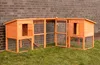 A wooden chicken coop with an attached run, set up on a grassy lawn in front of a brick wall. Produktbild-Vorschau
