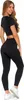 A woman wearing black leggings and a black crop top, posing against a white background. Produktbild-Vorschau