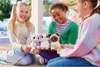 Three young girls are sitting on the floor, holding and playing with stuffed cat toys. Podgląd zdjęcia produktu