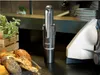 A GRAEF Akkusauger Krümelchef is placed on a counter next to a display of bread and pastries, with a white appliance to the right. Podgląd zdjęcia produktu