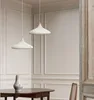 Two white pendant lamps hang over a wooden table with a vase on it, in a room with white paneled walls. Produktbild-Vorschau