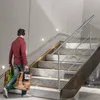 A person walks up a marble staircase carrying shopping bags. Náhľad obrázku produktu