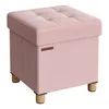 A pink upholstered storage ottoman with tufted top and wooden legs, set against a white background. Náhled obrázku produktu