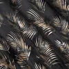A close-up of a dark fabric with a repeating pattern of gold and silver palm leaves. Produktbild-Vorschau