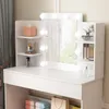 A white vanity table with a lighted mirror and shelves displaying makeup and decorative items. Náhled obrázku produktu