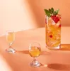 Three glasses of drinks are arranged on a peach-colored surface with soft lighting and shadows. Podgląd zdjęcia produktu