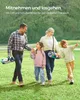 A family walking outdoors on a grassy area with trees in the background. Náhled obrázku produktu