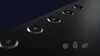 A close-up of the top surface of a black soundbar with several buttons and icons visible. Produktbild-Vorschau