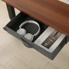 A close-up view of an open desk drawer containing a pair of white headphones and a book. Produktbild-Vorschau