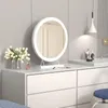 A white vanity table with a round LED makeup mirror, a vase of tulips, and perfume. Voir les images du produit