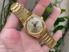A hand holding a gold Tissot watch with a green leafy background. Anteprima dell’immagine prodotto