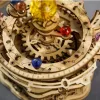 A close-up view of a wooden 3D puzzle model of the solar system, with colorful spheres representing planets and a large yellow sphere representing the sun. Produktbild-Vorschau