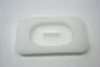 A white, rectangular silicone mold with rounded corners and an oval indentation in the center. A small, rectangular piece of white material is visible inside the indentation. Produktbild-Vorschau
