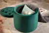 A dark green velvet ottoman with its lid off, revealing storage inside, placed on a rug. Produktbild-Vorschau