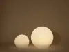 Two glowing spherical garden lights of different sizes are placed on a surface against a brown background. Produktbild-Vorschau