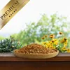 A wooden bowl filled with dried shrimp sits on a wooden surface, with green foliage and yellow flowers in the background. Produktbild-Vorschau
