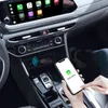 A person is holding a smartphone in a car, with a wireless CarPlay adapter in the center console. Produktbild-Vorschau
