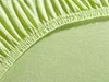 A close-up view of a light green jersey fitted sheet with elastic gathering along the edge. Produktbild-Vorschau