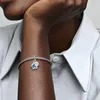 A close-up shot of a person's arm wearing a Pandora charm bracelet with a blue butterfly charm. Produktbild-Vorschau