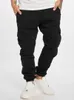 A person wearing black cargo jogging pants and white sneakers. Anteprima dell’immagine prodotto