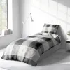 A neatly made bed with a checkered duvet and pillow in a bright, minimalist room. Produktbild-Vorschau