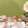 Hands assembling a wooden model of a classical gramophone, with various wooden parts and instructions laid out on a wooden table. Podgląd zdjęcia produktu