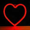 A red neon heart-shaped light is mounted on a black background and sits on a wooden surface. Voir les images du produit