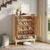 A shoe cabinet with its doors open, displaying shoes on shelves, in a hallway setting with stairs and a window in the background. Podgląd zdjęcia produktu