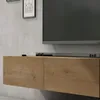 A close-up view of a modern, wall-mounted TV lowboard with a wood grain finish, mounted on a textured gray wall. A soundbar is placed on top of the lowboard, and a television is mounted above it. Produktbild-Vorschau
